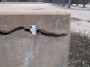 Picture shows a very wide crack along the perimeter of an ASR-affected foundation. A crack comparator is shown adjacent to the crack, and the crack appears to be inches in width 