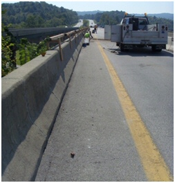 This figure shows the wall edge of concrete bridge structure. A truck is traveling down the road.