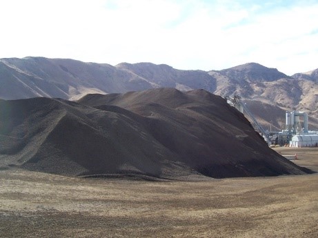 This is a large stockpile of reclaimed asphalt pavement. In the background is a hot mix asphalt plant.