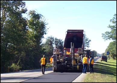 A paving crew is pictured along with equipment in the process of laying down a High RAP Warm Mix Asphalt mixture on State Route 11 in Deland, FL
