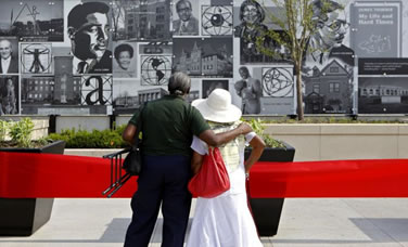 A photo of two people looking at a mural on the Cultural Wall.