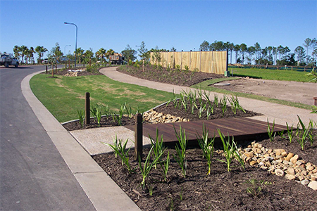 Swale and footbridge along road median.
