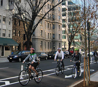 Bicyclists riding down a busy city street in a marked bike lane.