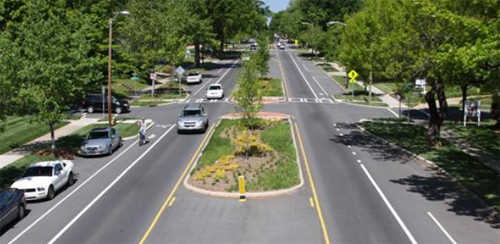 Two-lane road divided by median strips with trees.