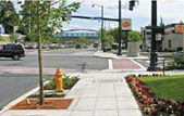 Intersection showing wide sidewalks and a pedestrian crosswalk.