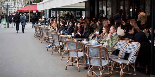 Scene showing patrons dining at an outside café.