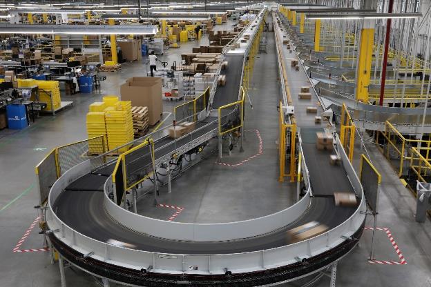 Photo of packages moving on automated conveyer belt inside Amazon fulfillment center.