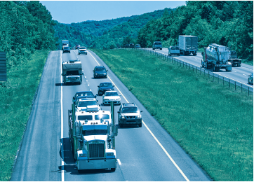 A variety of vehicles (trucks, cars, recreational vehicles) traveling on a highway.