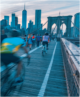 Bicyclists crossing a bridge toward a city