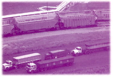 Picture of trucks along side railroad cars on a track.