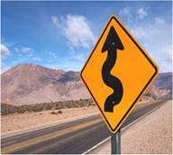 A mountain road with a curved arrow sign