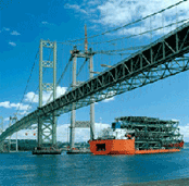 transport ship moored under bridge construction, delivering roadway sections
