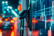 Composite image of a gasoline pump next to cars on a highway. Street lights and red car brake lights are reflected in the pump which also has lines similar to a data chart.