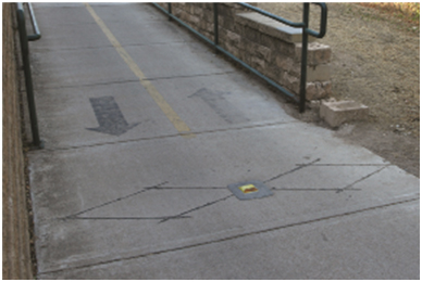 Examples of Inductance Loop Detector Shapes for Bicyclist Counting (Elongated Diamond Shape: Photo). This photo shows an installed elongated diamond loop on a shared use path.