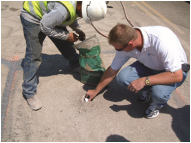 Wireless Magnetometer Being Installed for Motorized Traffic. This photo shows two technicians installing a magnetometer in the roadway surface.