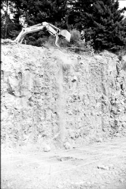 Photo of rocks being dropped off slope by an excavator