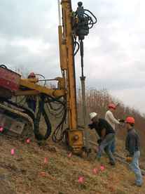 A track-mounted drilling rig being used to drive pins into a slope