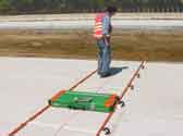 A worker inspects the MIT-Scan-2 device that rides on tracks as it is pulled across fresh or hardened concrete