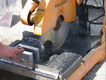 Photo: Superpave Performance Tester specimens are prepared using a clamped sawing device.