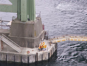 A photo of Japanese delegates to the 22nd U.S.-Japan Bridge Engineering Workshop tour the pier foundations of the 1950 Tacoma Narrows bridge. From this location, the delegation could view the foundation and substructure of the new Tacoma Narrows bridge.