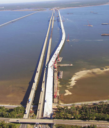 Figure 4. Photo. Escambia Bridge. Construction of a new I-10 bridge over Escambia Bay in Florida. The new bridge is being constructed next to the two existing bridges, which were damaged by Hurricane Ivan in September 2004. Floating work platforms are next to the partially constructed new bridge in the water.