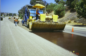 Figure 1. Photo. A spray unit prepares a road surface for chip sealing by administering a spray of binder.