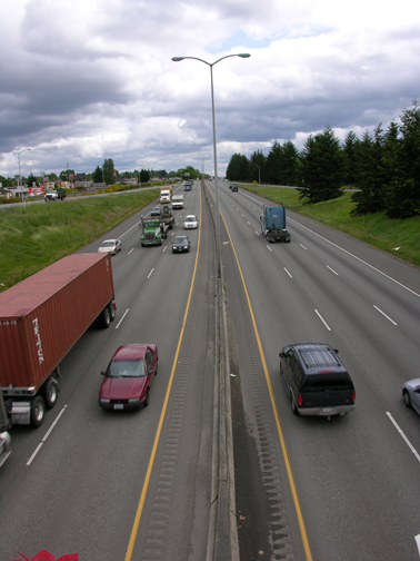 Figure 4. Photo. A view of I-5 in Washington State. Traffic is traveling in three lanes in each direction on the highway.