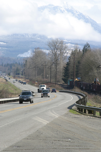 Figure 5. Photo. Vehicles travel on a two-lane rural road in Washington State.