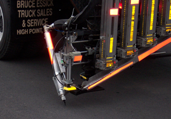Figure 2. Photo. A close-up of the Automated Roadway Pavement Marker System as it applies pavement markers to the roadway.