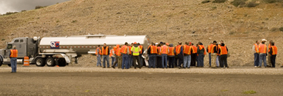 Figure 6. Photo. Participants at the Western Region In-Place Recycling Workshop stand on the side of I-80 in Pequop, Nevada, looking at equipment used in a cold in-place recycling project.