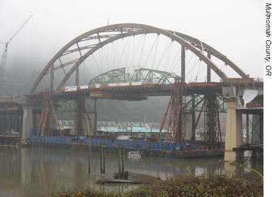 Figure 8. Photo. The Sauvie Island bridge is lowered onto the bridge piers.