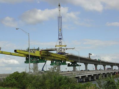 Figure 4. Photo. Construction of the Lee Roy Selmon Crosstown Expressway Expansion in Tampa, Florida. To expand the Expressway, a three-lane elevated cantilever structure is being built in the median. A construction crane and scaffolding are visible.