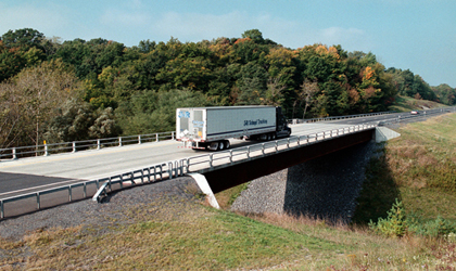 Photo. A tractor-trailer truck crosses a bridge.