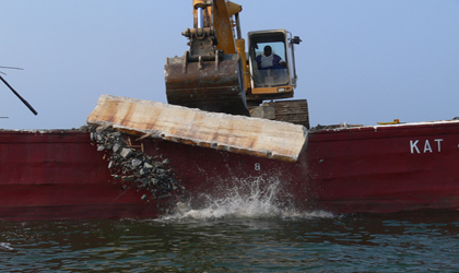 Photo. A bulldozer places a concrete barrier from the old Woodrow Wilson Bridge outside of Washington, DC, at Tangier Reef in Tangier Sound.