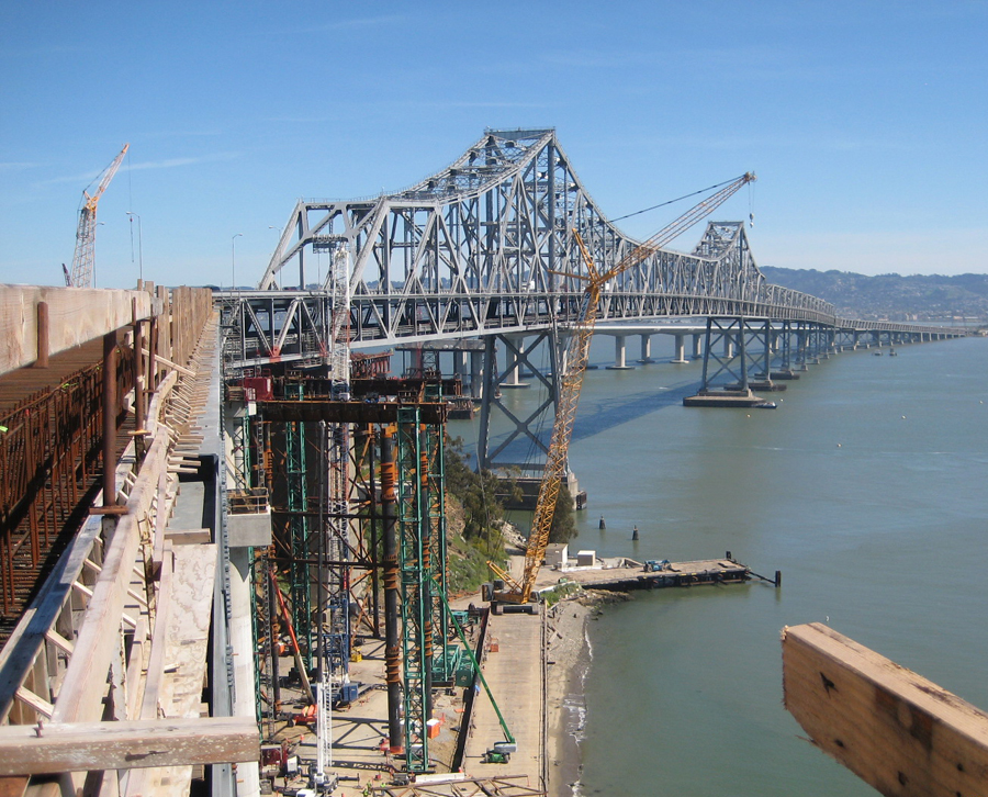 A view of California's San Francisco-Oakland East Bay Bridge under construction. Cranes and scaffolding are visible.
