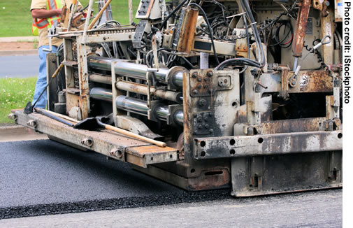 A close-up shot of a paver laying down asphalt.