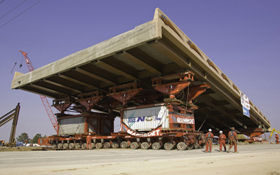 Figure 6. Photo. A close-up shot of a self-propelled modular transporter (SPMT) used to move and replace the 4500 South bridge in Salt Lake City, Utah, in a single weekend. The bridge is jacked up on the SPMT.