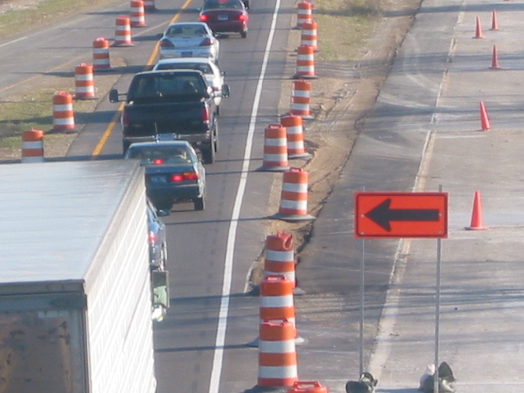 Figure 1. Photo. A view of traffic proceeding through a work zone. The image shows a closed lane to the right with one lane of traffic flowing on the left.