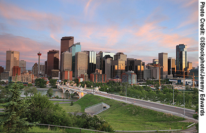 The Calgary skyline at sunset in Alberta, Canada, with parkland in the foreground.