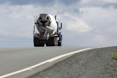 A view of the back of a cement truck driving down a highway.