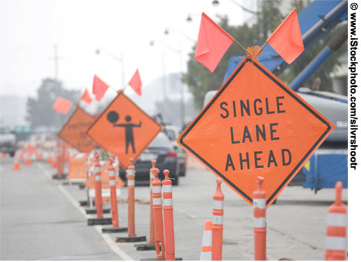 Traffic approaches a work zone. An up-close view of a "SINGLE LANE AHEAD" sign is in the foreground.