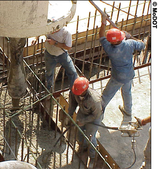 Three workers pour concrete for the New I-64 project in St. Louis, MO.