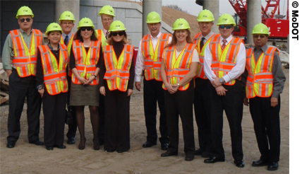 Eleven members of the Best Practices in Project Delivery Management scanning tour are seen in a group photo. Scan team members are wearing hard hats and safety vests.