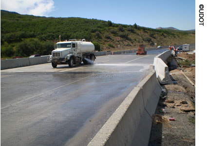 Construction on Interstate 80 in Salt Lake County, Utah, where four bridges were constructed offsite and moved into place over a 37-hour span. A truck is visible in the foreground of one of the four new bridges, with another construction vehicle, traffic cones, barrels, and other construction equipment in the background.