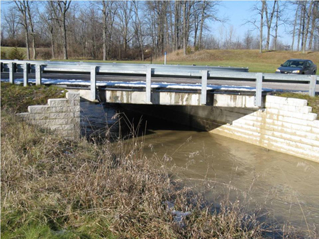 A side view of the Vine Street bridge in Defiance County, Ohio. A car travels over the bridge. The bridge was constructed using the Geosynthetic Reinforced Soil Integrated Bridge System.
