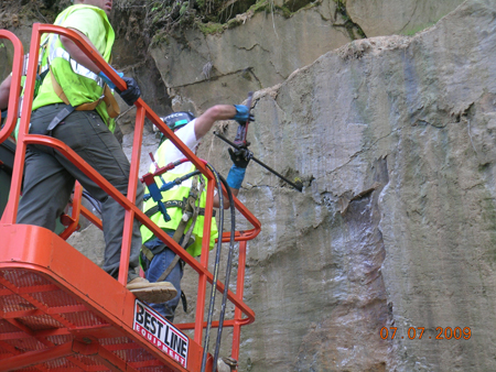 Figure 3. Photo. Two workers prepare a rock cut slope for injection of polyurethane resin or "rock glue" on the George Washington Memorial Parkway in Arlington, VA.