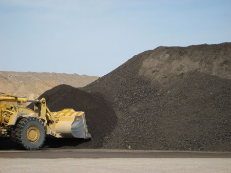 A front loader shovels a stockpile of reclaimed asphalt pavement (RAP).