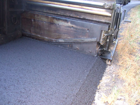 A paving machine creates the Safety Edge on an asphalt pavement, shaping the edge of the pavement to approximately 30 degrees.
