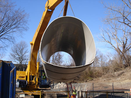 A crane lifts material for a concrete arch sewer rehabilitation project in Clifton, New Jersey. As part of the project, a custom-fabricated liner was installed in the sewer pipe.