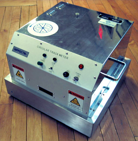 A closeup view of the Circular Texture Meter. The front of the equipment shows warning labels and a number of control knobs.